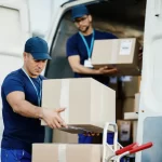 two movers unloading Cargo boxes from cargo van